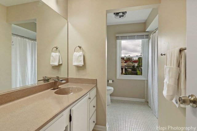 bathroom with toilet, baseboards, and vanity