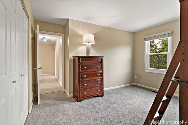 bedroom featuring light colored carpet, a closet, and baseboards
