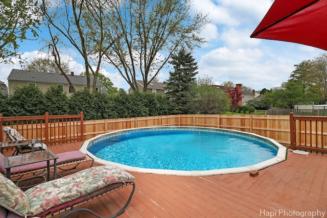 view of pool with a fenced backyard and a deck