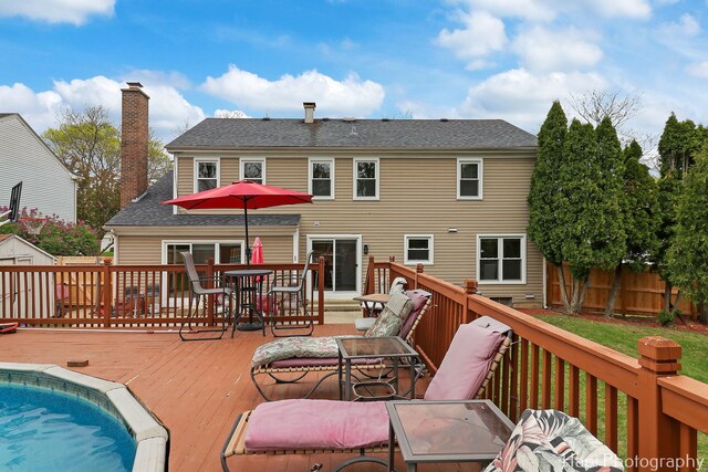 rear view of property featuring a wooden deck, outdoor dining area, and fence