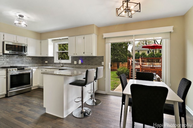 kitchen featuring appliances with stainless steel finishes, a sink, a peninsula, and backsplash