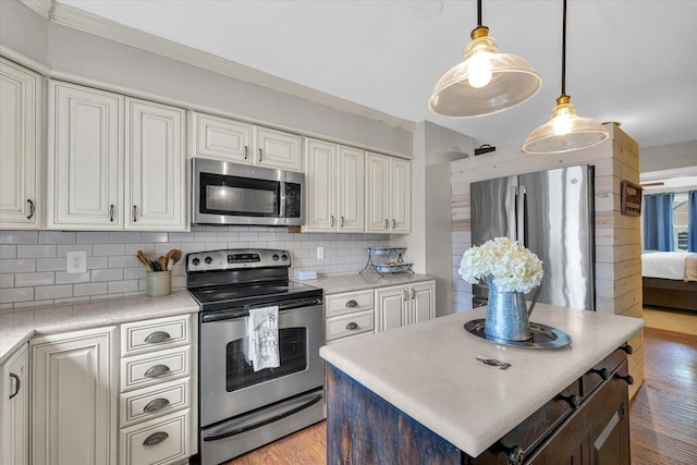 kitchen with light wood-style flooring, stainless steel appliances, light countertops, decorative backsplash, and ornamental molding