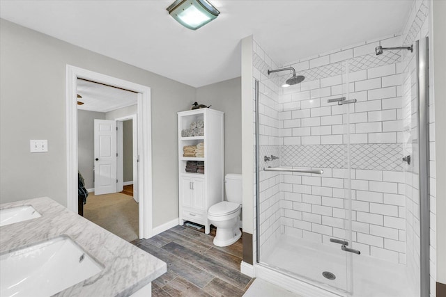 full bathroom featuring toilet, wood finished floors, a stall shower, and a sink