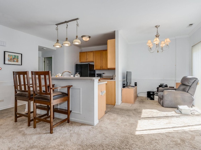 kitchen with light colored carpet, a breakfast bar, freestanding refrigerator, decorative light fixtures, and a notable chandelier