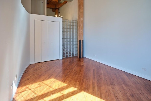 unfurnished bedroom featuring baseboards, wood finished floors, and a closet