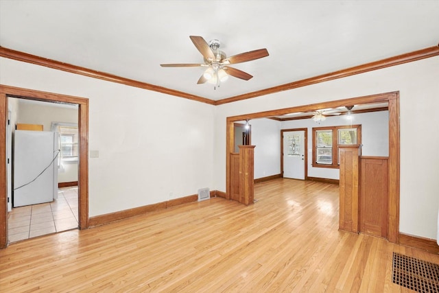 spare room featuring crown molding, ceiling fan, light wood-style floors, and visible vents