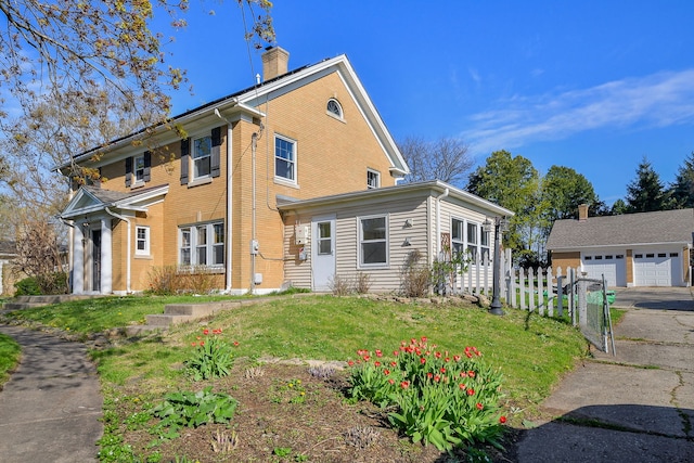 exterior space featuring a lawn, fence, a chimney, and a detached garage