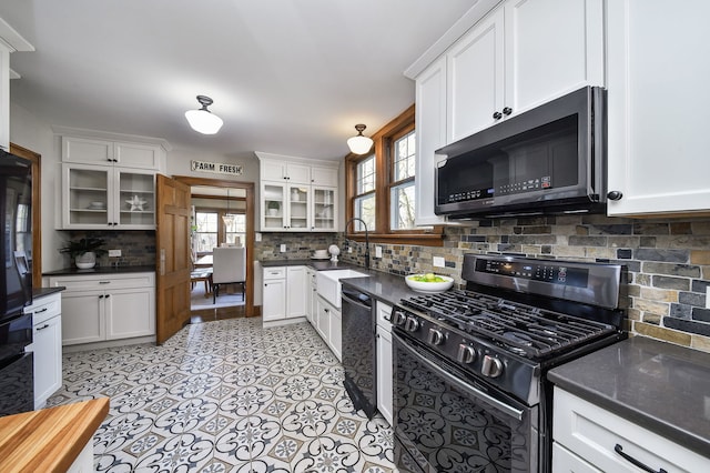 kitchen with a sink, dark countertops, decorative backsplash, and gas range