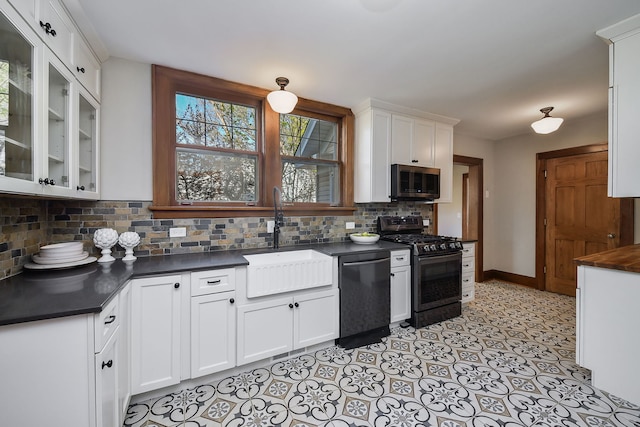 kitchen featuring dark countertops, a sink, dishwasher, stainless steel microwave, and gas range