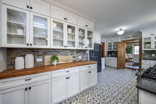 kitchen with black fridge with ice dispenser, wood counters, white cabinets, and tasteful backsplash