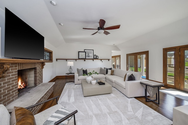 living room featuring a brick fireplace, plenty of natural light, wood finished floors, and lofted ceiling