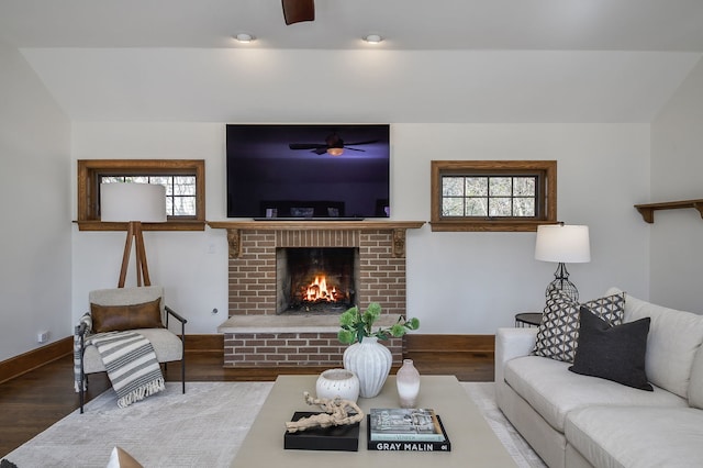 living room featuring a brick fireplace, ceiling fan, wood finished floors, and a wealth of natural light