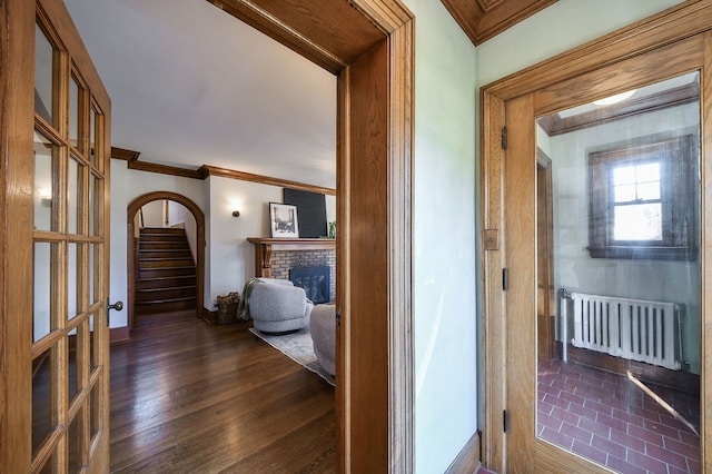 hall with dark wood finished floors, stairway, baseboards, radiator, and ornamental molding