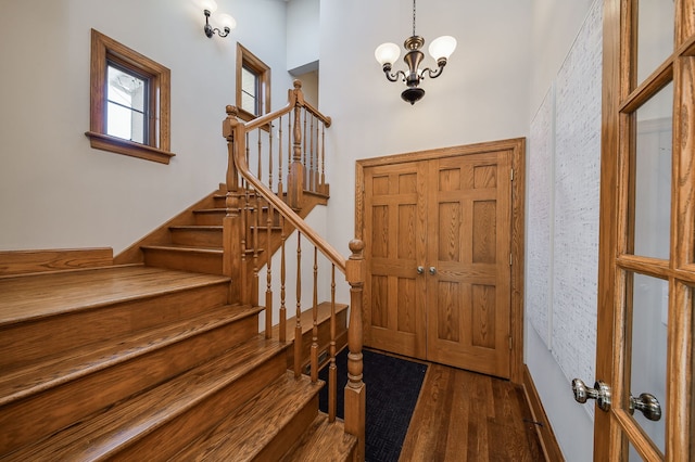 entrance foyer with an inviting chandelier, dark wood-style floors, and stairway