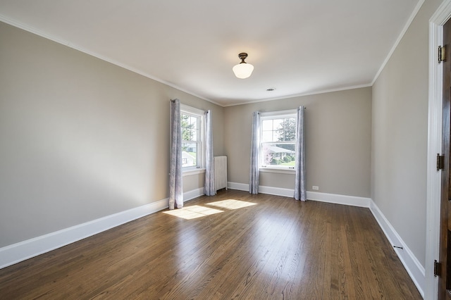 empty room with dark wood-type flooring, baseboards, crown molding, and radiator heating unit