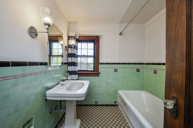 full bathroom with tile walls, a bathing tub, a wainscoted wall, and tile patterned floors