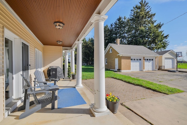 view of patio / terrace featuring a garage, an outbuilding, and a porch