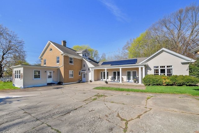 rear view of house featuring covered porch and solar panels
