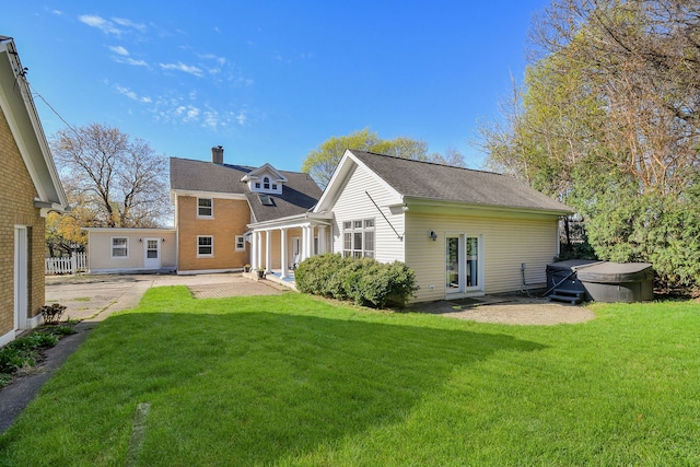 back of house with a patio, a hot tub, a yard, and a chimney