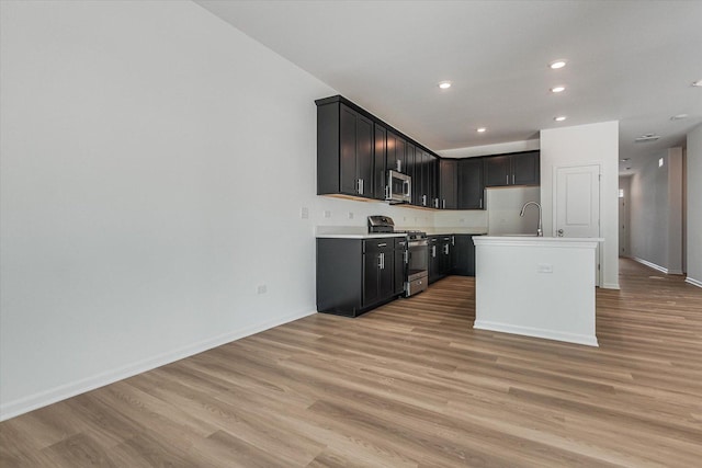 4 Harborside Way, Hawthorn Woods, IL 60047 - kitchen with a center island with sink, baseboards, light wood-style flooring, light countertops, and appliances with stainless steel finishes
