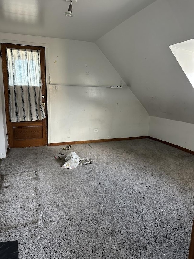 additional living space featuring carpet flooring, vaulted ceiling, and baseboards