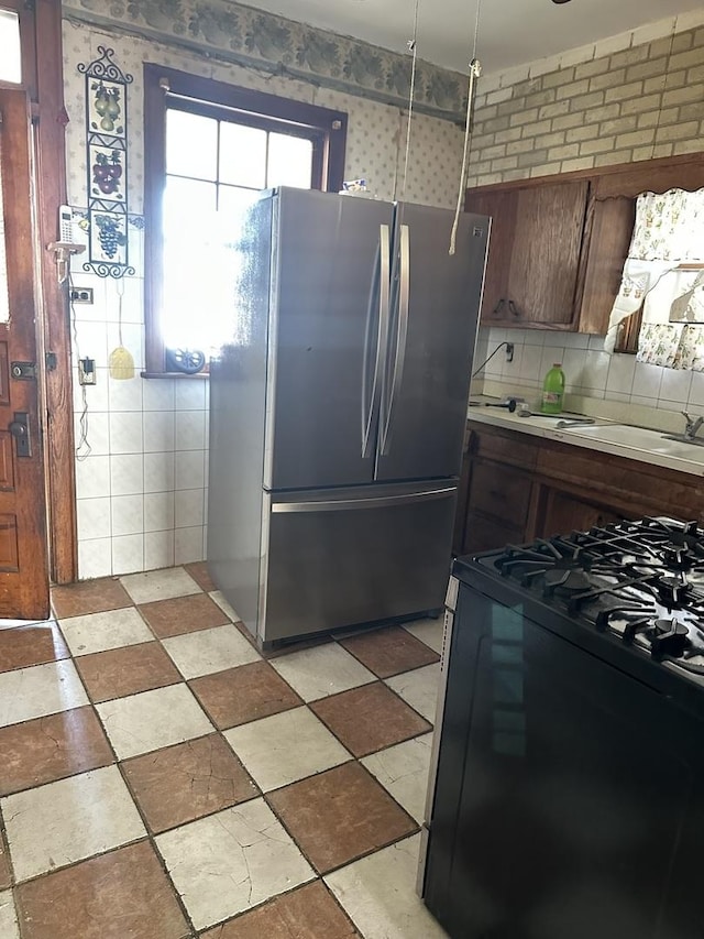 kitchen with gas stove, a sink, freestanding refrigerator, and light countertops