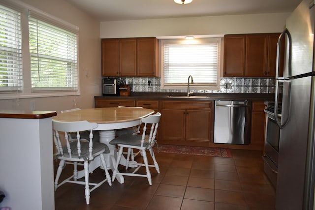 kitchen featuring a sink, brown cabinetry, backsplash, and appliances with stainless steel finishes