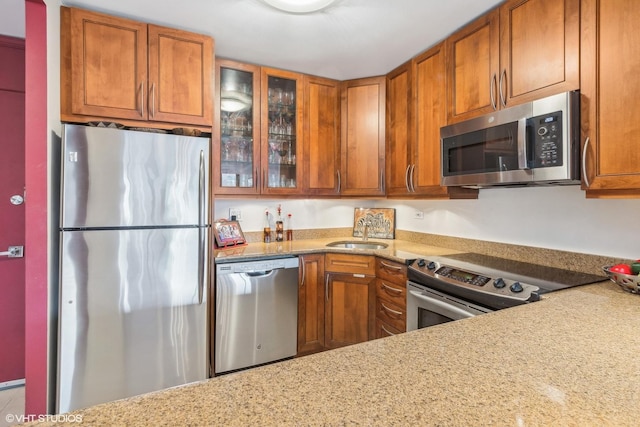 1555 N Sandburg Ter Unit 115K, Chicago, IL 60610 - kitchen with glass insert cabinets, a sink, appliances with stainless steel finishes, and brown cabinetry