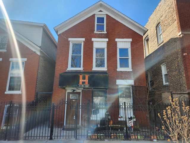 traditional-style house featuring brick siding and a fenced front yard