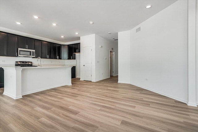 kitchen with a sink, visible vents, light wood-style flooring, light countertops, and appliances with stainless steel finishes