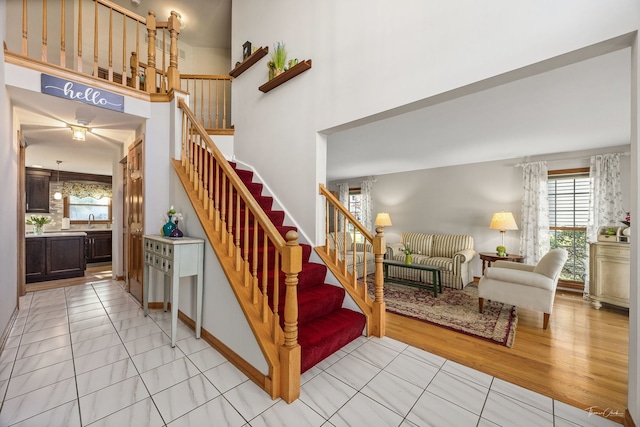 stairs featuring a ceiling fan, a towering ceiling, and tile patterned floors