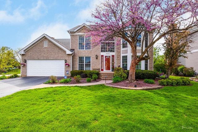 view of front facade featuring asphalt driveway, brick siding, a front lawn, and an attached garage