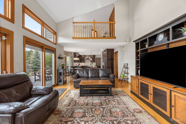 living area with high vaulted ceiling and light wood-style flooring