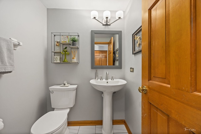 bathroom with toilet, tile patterned floors, baseboards, and a sink