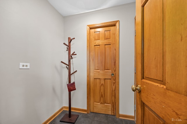 entryway featuring baseboards and dark tile patterned flooring
