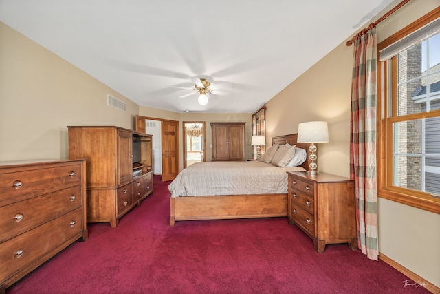 bedroom with multiple windows, dark colored carpet, a ceiling fan, and baseboards