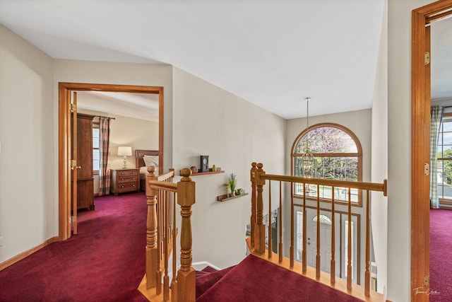 hallway featuring an upstairs landing, carpet flooring, and baseboards