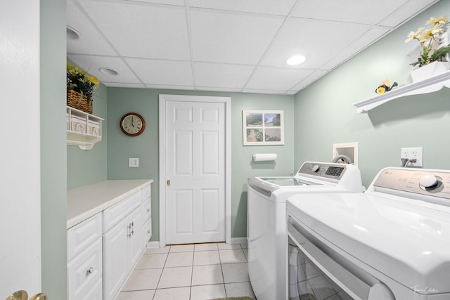 laundry room featuring washing machine and clothes dryer, light tile patterned flooring, cabinet space, and baseboards