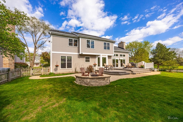back of property featuring a fire pit, a chimney, a wooden deck, and a gate