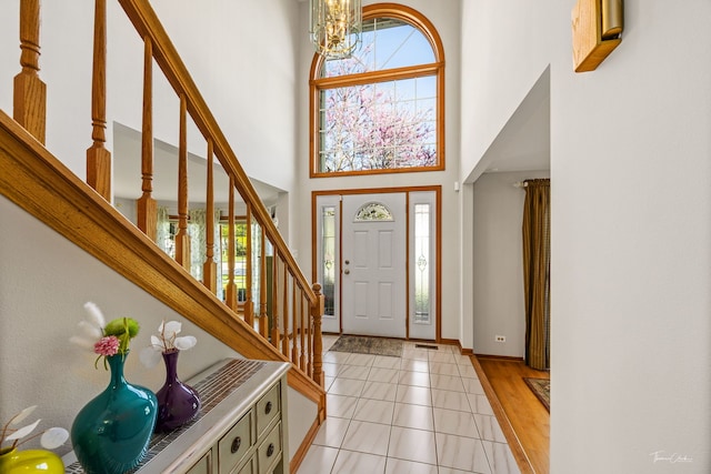entryway with plenty of natural light, stairway, a towering ceiling, baseboards, and light tile patterned floors