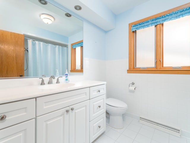 full bath with wainscoting, vanity, toilet, tile patterned floors, and tile walls
