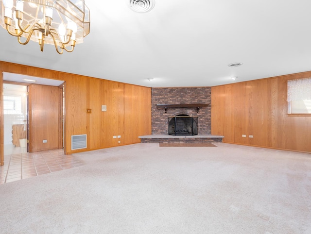 unfurnished living room featuring wooden walls, carpet, a fireplace, and visible vents