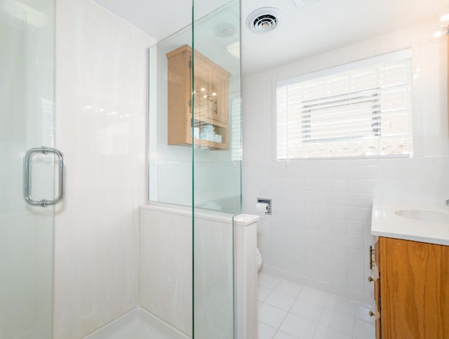 bathroom featuring tile walls, tile patterned flooring, a stall shower, and visible vents