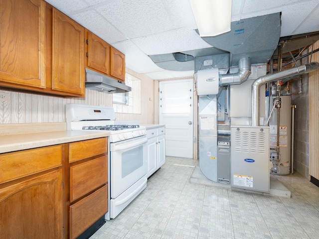 kitchen with brown cabinetry, white range with gas stovetop, light countertops, under cabinet range hood, and water heater