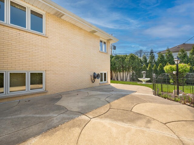 view of home's exterior featuring fence, a patio, and brick siding