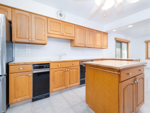 kitchen featuring a center island, dishwasher, a sink, light countertops, and freestanding refrigerator
