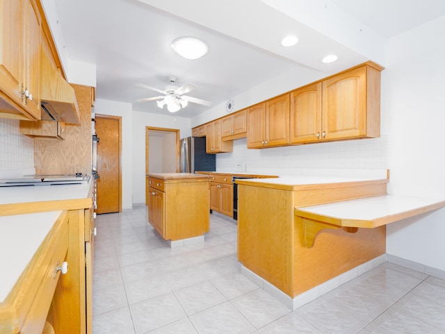 kitchen with freestanding refrigerator, a peninsula, ceiling fan, and tasteful backsplash