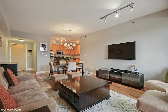living area with a chandelier, light wood finished floors, baseboards, and track lighting