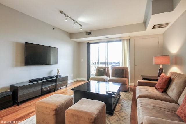 living room featuring light wood-type flooring, baseboards, and rail lighting