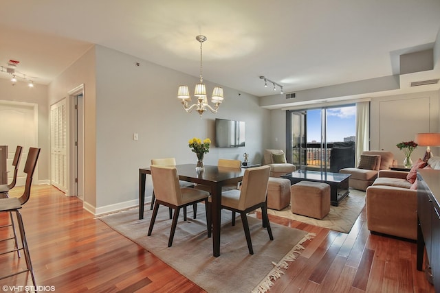 dining space featuring track lighting, light wood-style floors, a chandelier, and baseboards